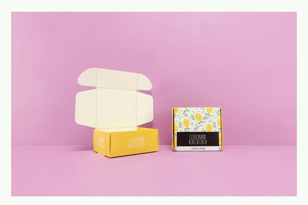 Geöffnete Klappschachtel mit gelbem und floralem Design Geöffnete Klappschachtel mit gelbem und floralem Design