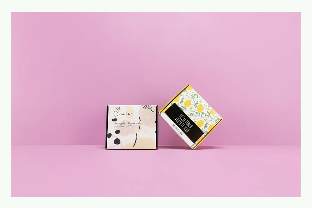 Zwei Klappschachteln mit floralem Design vor rosa Hintergrund Zwei Klappschachteln mit floralem Design vor rosa Hintergrund