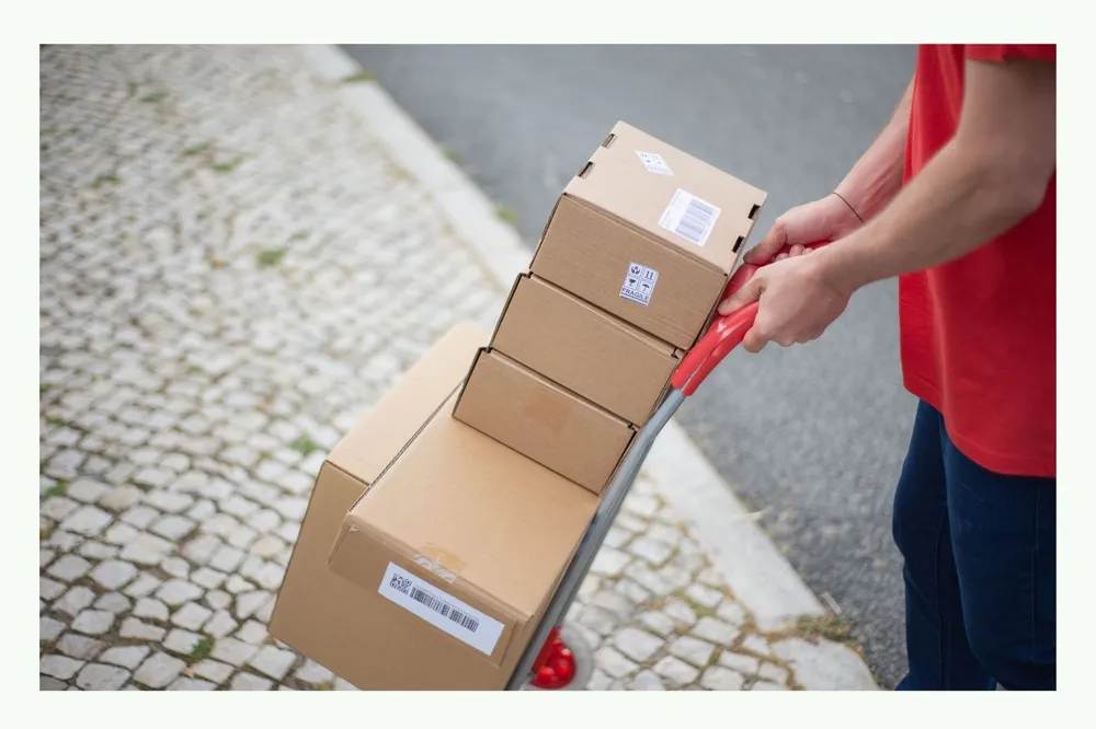 Person transporting several shipping cartons on a hand truck Person transporting several shipping cartons on a hand truck