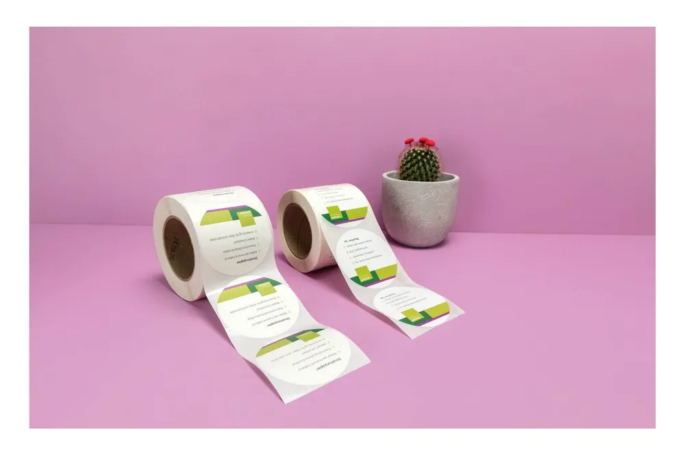 Zwei Rollen mit Runden und bedruckten Etiketten vor einem violetten Hintergrund
