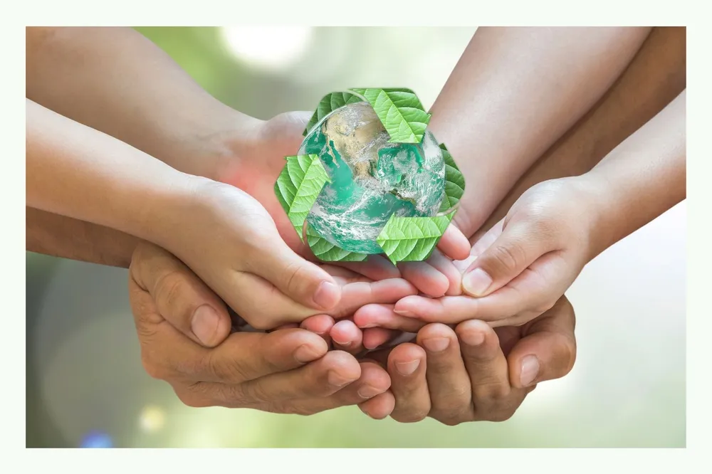 Diverse mani tengono un simbolo verde di riciclo in vetro Diverse mani tengono un simbolo verde di riciclo in vetro